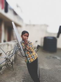 Boy standing by satellite dish outdoors