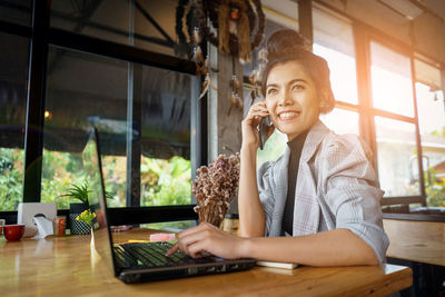 Young businesswoman using technologies while sitting at table