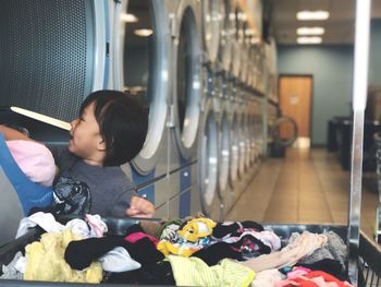 Close-up of boy putting laundry in washing machine in laundromat