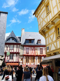 People on street by buildings in city against sky