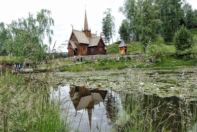 House by lake against sky
