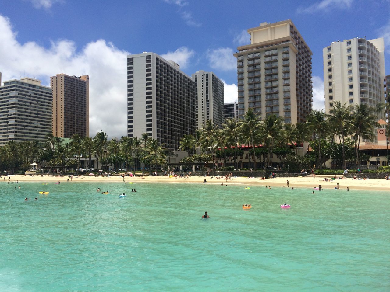 water, building exterior, sea, sky, architecture, waterfront, city, built structure, blue, large group of people, beach, leisure activity, vacations, tree, lifestyles, cloud - sky, swimming pool, enjoyment, skyscraper