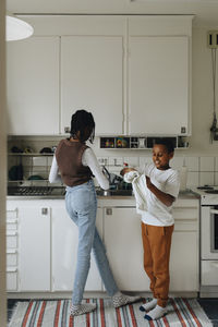 Brother and sister cleaning kitchen utensils at home