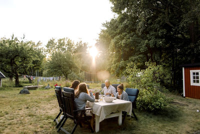 Smiling family enjoying while sitting by dining table in yard