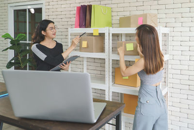 Young woman using mobile phone while standing in office