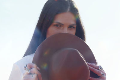 Portrait of young woman wearing hat against white background