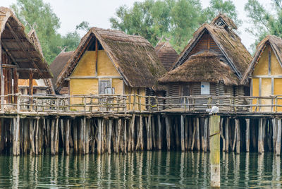 Wooden house by lake against sky