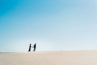 People on beach against clear sky