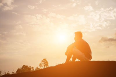 Silhouette man standing on rock against sky during sunset