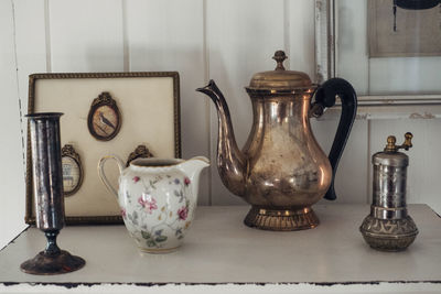 Old-fashioned kettle and jug by picture frame on table