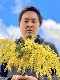 Portrait of man against yellow flowering plants against sky