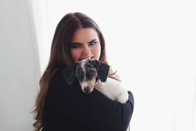 Portrait of young woman with dog against wall