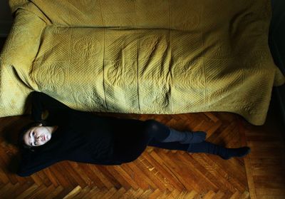 High angle view of woman lying on floor by sofa at home