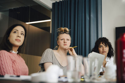 Transgender professional sitting amidst businesswomen in board room during meeting