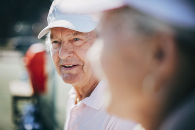 Close-up of senior man with friend at tennis court