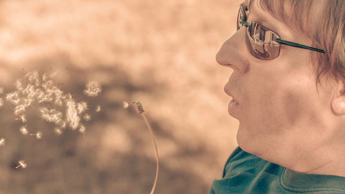 Close-up of man blowing dandelion