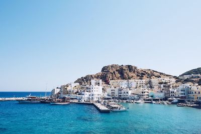 Boats in sea against clear blue sky