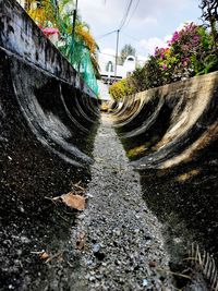 Surface level of wet street against sky in city