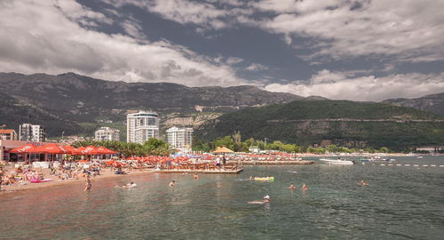 Group of people by sea against buildings in city