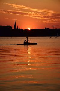 Silhouette person in sea against sky during sunset