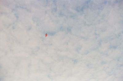Low angle view of red paragliding against sky