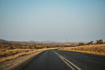 Road passing through landscape against clear sky