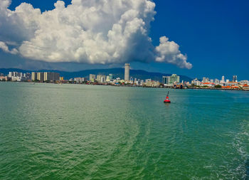 Scenic view of sea by buildings against sky
