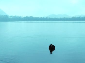 Man standing in lake against sky