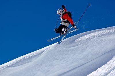 Low angle view of umbrella on snowcapped mountain against blue sky