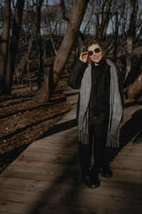 Portrait of young woman standing against tree trunk