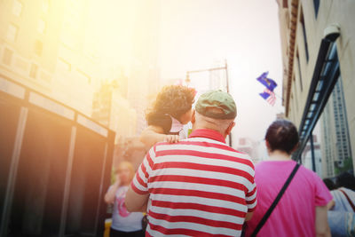 Grandfather carrying girl while walking on street