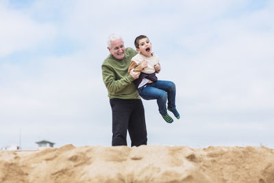 Grandfather holding his grandson on the beach