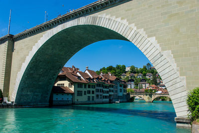 Arch bridge over river against buildings