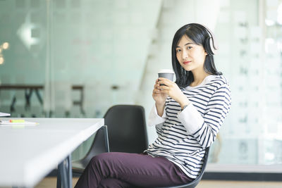 Young woman using mobile phone while sitting in cup