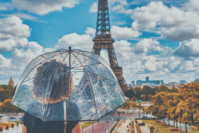 Rear view of woman holding umbrella standing against eiffel tower