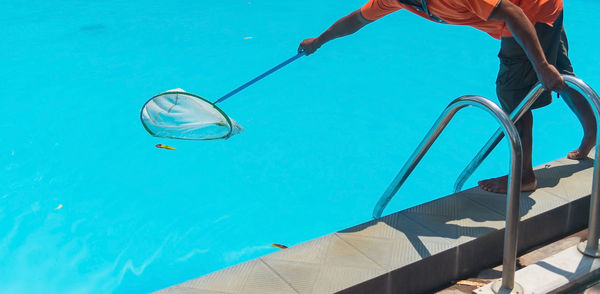 Low angle view of man swimming in pool against blue sky