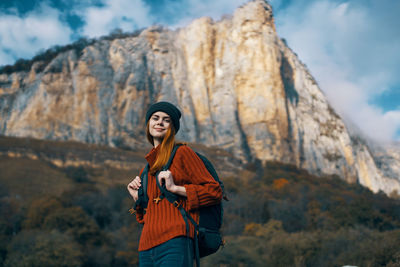 Portrait of young woman standing on mountain against sky