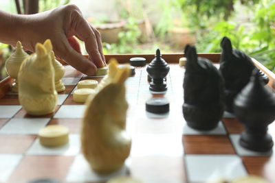 Cropped hand playing chess by window