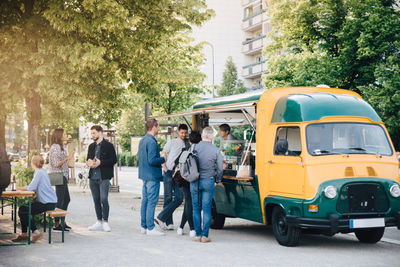 Male and female customers standing by food truck