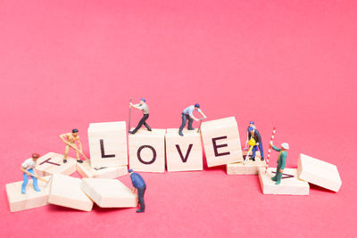 Figurines on toy blocks with love text against colored background