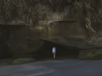 Young woman looking at cave at the beach