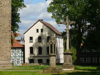 Houses and trees on field against sky