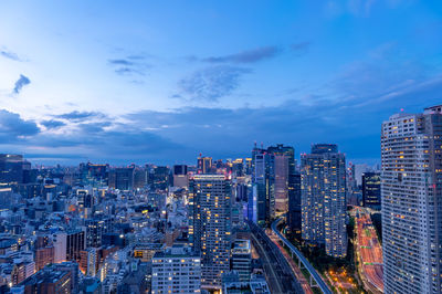 Illuminated buildings in city against sky at dusk