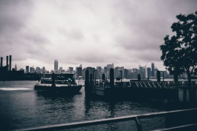 Boats sailing in river with city in background