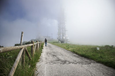 Rear view of man walking on footpath