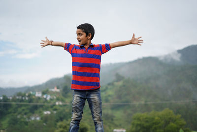 Full length of child standing on mountain against sky