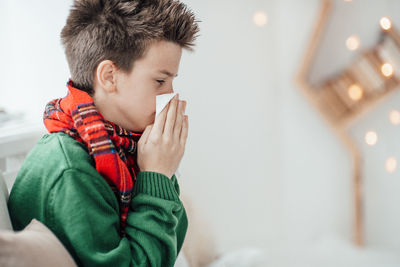 Close-up of boy sneezing at home