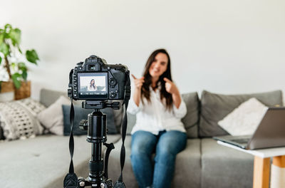 Selective focus photo of woman sitting on sofa, making video for social media