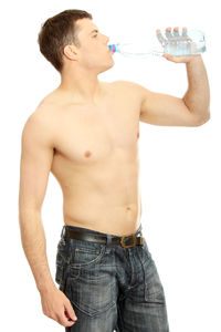 Midsection of shirtless man drinking glass against white background