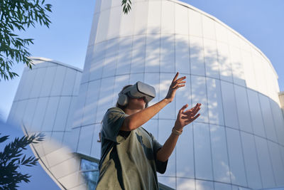 Low angle view of woman standing against blue sky